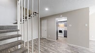 Located at 12250 Abrams Rd in Dallas, TX, this two-story, one-bedroom, one-bathroom unit offers a well-designed layout spread across two floors. The main level hosts the combined kitchen and living area, featuring light wood-look flooring throughout. The living room is a standout space, boasting dramatically high ceilings and a classic fireplace with a white mantle and dark tile surround, creating a warm and inviting focal point. The kitchen is efficiently designed with gray cabinetry, light quartz-style countertops, and white appliances including an electric range and refrigerator. Upstairs, the generously sized bedroom features plush carpeting, a vaulted ceiling, and a window that brings in natural light. A dedicated closet provides practical storage. The bathroom is thoughtfully appointed with gray vanity cabinetry, a light countertop, a bright vanity light fixture, and wood-look flooring, with an adjacent wet area. Textured ceilings are present throughout, adding architectural character. The neutral color palette across all rooms creates a clean, cohesive aesthetic that is both modern and functional. This unit offers a comfortable and practical living experience in a convenient Dallas location.