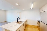 Located at 3519 Mercury Dr in Santa Maria, CA, this modern 2-bedroom, 2-bathroom residence offers a clean, contemporary design across a single floor. Light wood flooring flows consistently throughout all living areas, lending warmth and visual continuity to the space.

The open-concept kitchen and living area serves as the heart of the home. The kitchen is outfitted with light wood cabinetry, stainless steel appliances including a refrigerator, range, and microwave, and a central island featuring striking white stone countertops with subtle veining and a matte black faucet over a stainless steel sink. Recessed lighting illuminates the space efficiently.

The primary bedroom is generously sized, offering access to a private balcony through sliding glass doors that invite abundant natural light and views of the surrounding community. It includes a walk-in closet with built-in hanging rods and direct access to an en-suite bathroom. The second bedroom features a large window with open outdoor views and recessed lighting.

Both bathrooms maintain a consistent modern aesthetic, each equipped with a soaking tub and shower combination, white tile surrounds, backlit vanity mirrors, light wood cabinetry, white countertops, and matte black hardware accents. A hallway connects all rooms, contributing to a logical and efficient layout throughout this well-appointed residence.