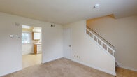 Located at 6701 Dartmouth Avenue in Richmond, Virginia, this two-story home is thoughtfully laid out across two equally sized floors. The main level features a carpeted living room with neutral warm-toned walls, white painted staircase with spindle railings, and direct access to the kitchen. The kitchen is equipped with white cabinetry accented by wood-toned trim, a full suite of white appliances including a dishwasher, electric range, and refrigerator, a single-basin sink, and light tile flooring beneath a skylight-style overhead fixture. A window allows natural light to fill the space.

Upstairs, two carpeted bedrooms provide comfortable accommodations. The spacious primary bedroom connects to the shared full bathroom and features a window with outdoor views. The second bedroom also benefits from a window bringing in natural light. Both rooms feature neutral walls and carpet flooring. Two closets provide practical storage throughout the upper level.

The full bathroom is finished with tile flooring, a tub-shower combination with white tile surround, a single vanity, and a window that brightens the space naturally. A hallway connects the upstairs rooms efficiently. Throughout the home, a clean, neutral palette and consistent carpeting create a cohesive, move-in ready environment.