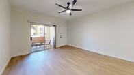 Located at 7401 E Speedway Blvd in Tucson, AZ, this efficiently designed one-bedroom, one-bathroom unit offers a clean, modern aesthetic throughout its single-floor layout. Light wood-style flooring flows through the main living areas, complemented by crisp white walls and black ceiling fans that add a contemporary contrast.

The open living room is bright and airy, with sliding glass doors leading to a private patio — an ideal spot for enjoying Tucson's outdoor lifestyle. The space connects seamlessly to the kitchen, which features light cabinetry and ample counter space.

The bedroom is a well-proportioned retreat finished with plush carpeting, a ceiling fan with light, and a window that allows natural light to fill the room. A dedicated closet provides convenient storage, and direct access to the bathroom adds practicality.

The bathroom is outfitted with light wood-tone cabinetry topped with a white countertop, a tub-shower combination with a clean white surround and a styled curtain, and a tall storage cabinet with matte black hardware. The unit also includes an in-unit laundry area, adding everyday convenience. Overall, the space presents a cohesive, updated design with functional flow throughout.