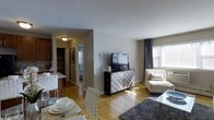This 1-bedroom, 1-bathroom residence is thoughtfully designed to maximize comfort and functionality across a single floor. The open-concept living and dining area serves as the heart of the home, featuring warm hardwood flooring that flows seamlessly throughout, lending a cohesive and inviting feel to the space. Natural light pours in through windows dressed with elegant draping curtains, creating a bright and airy atmosphere. The living area provides ample room for relaxing and entertaining, complemented by clean, neutral-toned walls that offer a versatile backdrop for any décor style. A dedicated dining space sits adjacent to the kitchen, which features cabinetry and a breakfast bar-style counter — ideal for casual meals or additional prep space. A hallway connects the main living areas to the private bedroom, which benefits from natural light and a peaceful setting. The bathroom is conveniently accessible from the hall. Throughout the residence, the layout is efficient and well-considered, making excellent use of every square foot. The warm hardwood floors, neutral palette, and natural light combine to create a comfortable, move-in-ready living environment.