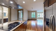 Located at 2121 N Westmoreland St in Arlington, VA, this well-appointed 2-bedroom, 2-bathroom residence offers a thoughtfully designed single-floor layout with generous living space. The open-concept kitchen and living area serves as the heart of the home, featuring rich dark wood cabinetry, granite countertops with a mosaic tile backsplash, stainless steel appliances including a double wall oven and built-in microwave, a sleek electric cooktop, and a stainless range hood. Large windows throughout flood the space with natural light and provide views of the surrounding neighborhood. Hardwood floors extend through the kitchen and living areas, complemented by track and recessed lighting, while plush carpet lines the bedrooms. The primary bedroom is a comfortable retreat with a ceiling fan, large window, and direct access to a well-sized closet. Its en-suite bathroom is elegantly finished with tile flooring, a double vanity with dark wood cabinetry, a soaking tub, and a glass-enclosed walk-in shower. The second bedroom mirrors the warm tones and carpeted comfort of the primary. Additional highlights include a dedicated in-unit laundry room with full-size washer and dryer, a hallway connecting all rooms efficiently, and tile flooring in wet areas throughout.