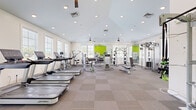 Located at 4037 Lamplighter Dr in North Chesterfield, VA, this fitness center offers a comprehensive, single-floor workout facility designed to support a wide range of exercise routines. The space is bright and welcoming, featuring white walls accented by bold lime-green focal walls that add energy and visual interest to the environment. Large windows with blinds line the walls, flooding the interior with abundant natural light and offering views of the surrounding outdoor area.

The fitness center is thoughtfully laid out to maximize usability. A dedicated cardio zone features multiple treadmills and elliptical machines from Life Fitness, while a strength training area is equipped with multi-station cable machines, weight benches, and a cable functional trainer. A free weight section includes a full rack of dumbbells alongside battle ropes and resistance bands. Full-length mirrors along one wall expand the sense of space and allow for proper form checks during workouts.

Overhead, vaulted ceilings with recessed lighting and ceiling fans enhance airflow and maintain a comfortable atmosphere. The flooring consists of durable, two-tone carpet tiles suited for high-traffic fitness use. The overall design is clean, modern, and functional, making this fitness center a well-rounded amenity for residents and users in the North Chesterfield community.