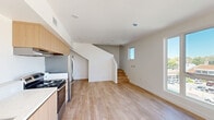 Located on Ventura Blvd in Woodland Hills, CA, this contemporary two-story home offers three bedrooms and two bathrooms thoughtfully distributed across two floors. The main level provides a generous open-plan living and kitchen area, where light hardwood-style flooring and crisp white walls create a clean, modern aesthetic. The kitchen is outfitted with light wood cabinetry, white countertops, stainless steel appliances including a range, dishwasher, and refrigerator, all accented by recessed lighting overhead. Large windows on the main floor fill the living area with natural light and provide views of the surrounding Woodland Hills neighborhood. A wood-tread staircase connects the two levels, adding warmth to the interior. The upper floor houses the bedrooms, including a spacious primary bedroom, each featuring the same light hardwood flooring and generous windows that invite abundant natural light. The two bathrooms are finished with stone-look countertops, undermount sinks, chrome fixtures, and frameless mirrors, conveying a clean, contemporary style. Three closets and two hallways ensure practical storage and circulation throughout. The overall ambiance is bright, minimal, and move-in ready.