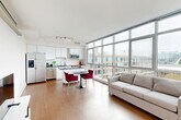Located at 1151 4th St SW in Washington, DC's Southwest Waterfront neighborhood, this modern 2-bedroom, 2-bathroom residence offers a well-designed single-floor layout with a clean, contemporary aesthetic throughout. The open-concept kitchen and living area serves as the heart of the home, anchored by large floor-to-ceiling windows that flood the space with natural light and frame sweeping urban views. The kitchen is outfitted with sleek white cabinetry, a white subway tile backsplash, stainless steel appliances, and a granite-topped island, all set above warm hardwood-style flooring that continues into the living area. The primary bedroom is a comfortable retreat featuring a ceiling fan, a walk-in closet, and a private en-suite bathroom with a glass-enclosed stand-up shower finished in white tile. The second bedroom offers plush carpeting, a dedicated closet with built-in shelving, and a transom-style window that brings in soft, indirect light. The second bathroom features a full tub-shower combination with classic white subway tile and chrome fixtures. Both hallways connect the spaces efficiently, while two closets provide ample storage. The residence maintains a bright, minimalist palette of white walls and neutral tones throughout, creating a calm and cohesive atmosphere.