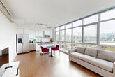 Located at 1151 4th St SW in Washington, DC's Southwest Waterfront neighborhood, this modern 2-bedroom, 2-bathroom residence offers a well-designed single-floor layout with a clean, contemporary aesthetic throughout. The open-concept kitchen and living area serves as the heart of the home, anchored by large floor-to-ceiling windows that flood the space with natural light and frame sweeping urban views. The kitchen is outfitted with sleek white cabinetry, a white subway tile backsplash, stainless steel appliances, and a granite-topped island, all set above warm hardwood-style flooring that continues into the living area. The primary bedroom is a comfortable retreat featuring a ceiling fan, a walk-in closet, and a private en-suite bathroom with a glass-enclosed stand-up shower finished in white tile. The second bedroom offers plush carpeting, a dedicated closet with built-in shelving, and a transom-style window that brings in soft, indirect light. The second bathroom features a full tub-shower combination with classic white subway tile and chrome fixtures. Both hallways connect the spaces efficiently, while two closets provide ample storage. The residence maintains a bright, minimalist palette of white walls and neutral tones throughout, creating a calm and cohesive atmosphere.