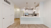 Located in the Collier Hills neighborhood of Atlanta, Georgia, this single-floor residence offers a clean, modern aesthetic defined by light tones, crown molding, and light wood-style flooring throughout the main living areas. The open-concept kitchen is a standout feature, showcasing white shaker cabinetry, quartz countertops, a gray subway tile backsplash, and a full suite of stainless steel appliances including a refrigerator, range, microwave, and dishwasher. Elegant pendant lighting hangs above the kitchen island, which also features an undermount sink. The adjoining living and dining areas are bright and airy, benefiting from large French doors topped with transom windows that invite generous natural light and provide views of the surrounding greenery. A ceiling fan adds comfort to the open living space. The bedrooms are carpeted for warmth and comfort, each featuring ceiling fans and ample natural light from large windows. The primary bedroom includes access to a walk-in closet. The bathroom is finished in crisp white tile, featuring a soaking tub and shower combination with polished chrome fixtures and wood-style flooring. Throughout the residence, white panel doors and consistent trim details contribute to a cohesive and welcoming atmosphere.