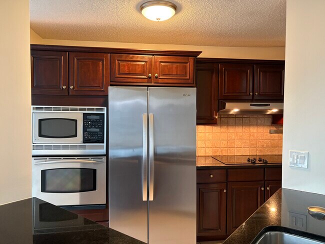 Cocina con encimeras de granito, gabinetes de madera maciza y electrodomésticos de acero inoxidable. - 25 Rockledge Ave