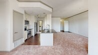 This 970-square-foot, single-floor apartment at 4699 Kittredge Street, Unit 3-323, in Denver, Colorado offers 2 bedrooms, 3 bathrooms, and a well-designed layout across one level. The open-concept kitchen is a standout feature, boasting white shaker cabinetry, dark granite countertops, a subway tile backsplash, stainless steel appliances including a range, microwave, dishwasher, and refrigerator, and a central island with a sink — all flowing directly into the carpeted living area. Natural light filters in through multiple windows, enhancing the bright, neutral color palette throughout. The primary bedroom measures 160 square feet and includes a ceiling fan and access to a spacious walk-in closet with built-in shelving and hanging rods. A second well-sized bedroom also features a walk-in closet. The bathrooms are finished with white cabinetry, dark granite vanity tops, large mirrors, and grey tile-surround tub and shower combinations. Dark hardwood-style flooring runs through the kitchen and bathrooms, while plush carpet covers the living and bedroom areas. A dedicated in-unit laundry room accommodates a full-size washer and dryer with additional shelving above. A connecting hallway ties all spaces together for a functional and cohesive floor plan.