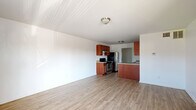 Located at 902 Gum Branch Rd in Jacksonville, NC, this single-floor, one-bedroom, one-bathroom unit offers a practical and well-organized layout. The open-concept living and kitchen area serves as the heart of the home, with light wood-style flooring flowing throughout, white walls, and flush-mount ceiling lighting that keeps the space feeling bright and clean. A bold black front door welcomes you into the living area, which features a window that brings in natural light and views of the surrounding exterior.

The kitchen is equipped with warm-toned, medium wood cabinetry, granite-look countertops, stainless steel appliances including a range and refrigerator, and a peninsula that separates it from the living area — providing both additional counter space and an informal dining or prep area. A sink is integrated into the peninsula for added convenience.

The bedroom offers a comfortable footprint with the same light wood-style flooring, a built-in closet with a hanging rod, and an electrical panel tucked neatly into the wall. An additional door in the bedroom provides access to a secondary space or utility area.

The bathroom includes a full tub-shower combination, a vanity with storage, and dark wood-style flooring, completing this straightforward and functional unit.