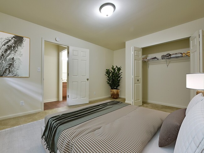 A bedroom with a closet and large window with blinds. - Grand Bend Club Apartments