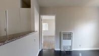 Located at 330 Waldo Ave in Pasadena, CA, this single-floor, one-bedroom, one-bathroom unit offers a practical and well-organized layout. The combined living and dining area features dark hardwood flooring and a wall-mounted heater unit, with an open pass-through to the kitchen that enhances the sense of connectivity throughout the main living space. The kitchen is equipped with white cabinetry, dark granite-style countertops, a gas range, a full-size refrigerator, and a double-basin sink positioned beneath a window with slatted blinds, allowing natural light to filter in. Tile flooring throughout the kitchen provides a clean, easy-to-maintain surface. The bedroom is a generously sized, carpeted room featuring two windows dressed with vertical blinds, a ceiling fan, and views of surrounding greenery. A dedicated walk-in closet with a full-length hanging rod and carpeted flooring offers ample storage. The bathroom includes a tub-shower combination surrounded by a distinctive checkerboard tile pattern in neutral beige and white tones, complemented by a pedestal-style vanity. The unit's neutral color palette and functional design make it a straightforward, comfortable living space in a well-established Pasadena neighborhood.
