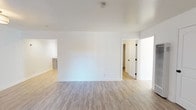This single-floor space presents a cohesive, move-in-ready interior defined by light wood-look luxury vinyl flooring that runs consistently throughout every room, tying the layout together with a clean, modern aesthetic. Crisp white walls and white trim complement the pale flooring, creating an airy, bright atmosphere across the unit.

The living area is generously proportioned, offering an open feel with a front entry door and vertical blinds that allow natural light to filter in. A wall heater is conveniently positioned nearby. The layout connects seamlessly to additional rooms, with interior doors featuring matte black hardware that adds a subtle contemporary contrast.

The kitchen is well-appointed with gray shaker-style cabinetry, marble-look countertops, and a full suite of stainless steel appliances including a range, dishwasher, and microwave. Recessed lighting and a window with vertical blinds keep the space bright and functional.

The bedrooms are comfortably sized, each receiving natural light through windows with vertical blinds. One bedroom includes a ceiling fan for added comfort.

The bathroom is thoughtfully designed with a gray double vanity, white countertop, ample drawer storage, a tub-shower combination, and a window above the tub. Light tile-look flooring ties the bathroom's clean, updated look together.