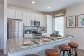 Located at 4251 Holly Springs Pkwy in Holly Springs, Georgia, this single-floor residence combines modern design with comfortable, functional living. The open-concept layout flows seamlessly from room to room, with wood-look flooring running through the main living areas and plush carpet in the bedrooms.

The kitchen is a standout feature, boasting tall white shaker cabinets, granite countertops, a subway tile backsplash, a large center island with a undermount sink, and a full suite of stainless steel appliances. Natural light fills the space through multiple windows dressed with wood blinds and sheer curtains.

The bright dining area is framed by a bay of windows on multiple walls, creating an airy, sunlit atmosphere ideal for gatherings. The living room offers a welcoming ambiance with a ceiling fan, large windows, and thoughtful design details.

The primary bedroom features a soft color palette with paneled wall accents, generous natural light, and plush carpet, offering a serene retreat. The secondary bedroom is equally well-sized and comfortable. The bathroom is finished with granite countertops, white cabinetry, wood-look flooring, and a tub-shower combination with white tile surround. Clean white five-panel interior doors complete the polished aesthetic throughout this thoughtfully designed home.