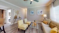 Located at 1400 El Camino Village Dr in Houston, TX, this well-appointed single-story residence offers a thoughtfully designed open-concept layout with consistent wood-look flooring throughout. The spacious living room features crown molding, a ceiling fan, large windows that invite natural light, and neutral warm-toned walls that create a welcoming ambiance. Adjacent to the living area, a dedicated dining space is framed by large windows with shuttered blinds and a stylish pendant light above a circular dining table. The kitchen is equipped with warm-toned cabinetry, white appliances, a skylight, a breakfast bar peninsula, and convenient access to a dedicated pantry or utility closet. Two well-proportioned bedrooms each feature crown molding, ceiling fans, and ample closet space. The primary bedroom includes a large window and an en-suite bathroom with an extended vanity, wood-look flooring, and a tub-shower combination. A second full bathroom mirrors this design, featuring a single-sink vanity and a tub-shower combo. A dedicated in-unit laundry room provides added convenience, housing a full-size washer and dryer with overhead shelving. The cohesive neutral palette and consistent finishes throughout lend the space a polished, move-in-ready appeal.