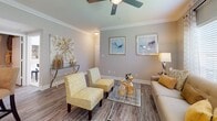 Located at 1400 El Camino Village Dr in Houston, TX, this well-appointed single-story residence offers a thoughtfully designed open-concept layout with consistent wood-look flooring throughout. The spacious living room features crown molding, a ceiling fan, large windows that invite natural light, and neutral warm-toned walls that create a welcoming ambiance. Adjacent to the living area, a dedicated dining space is framed by large windows with shuttered blinds and a stylish pendant light above a circular dining table. The kitchen is equipped with warm-toned cabinetry, white appliances, a skylight, a breakfast bar peninsula, and convenient access to a dedicated pantry or utility closet. Two well-proportioned bedrooms each feature crown molding, ceiling fans, and ample closet space. The primary bedroom includes a large window and an en-suite bathroom with an extended vanity, wood-look flooring, and a tub-shower combination. A second full bathroom mirrors this design, featuring a single-sink vanity and a tub-shower combo. A dedicated in-unit laundry room provides added convenience, housing a full-size washer and dryer with overhead shelving. The cohesive neutral palette and consistent finishes throughout lend the space a polished, move-in-ready appeal.