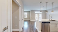Located in Katy, TX, this two-bedroom, one-bathroom residence offers a thoughtfully designed single-floor layout with modern finishes throughout. The open-concept kitchen and living area serves as the heart of the home, anchored by a large granite-topped island with an undermount sink and pendant lighting overhead. White cabinetry, a subway tile backsplash, and stainless steel appliances — including a refrigerator, range, and microwave — complete the kitchen. Wood-style plank flooring flows seamlessly throughout the entire unit, adding warmth and visual continuity. The living area benefits from multiple windows that invite an abundance of natural light, creating a bright and welcoming atmosphere. Both bedrooms are well-proportioned, each featuring neutral toned walls, wood-style flooring, a ceiling fan, and dedicated closet space with built-in shelving and hanging rods. The primary bedroom includes a spacious walk-in closet. The full bathroom is finished with subway tile surrounding the soaking tub and shower, a granite-topped vanity with a white cabinet base and matte black hardware, and wood-style flooring. A dedicated laundry area and ample closet storage add practical functionality to this clean, move-in ready space.