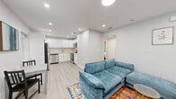 This thoughtfully laid-out 2-bedroom, 1-bathroom home makes excellent use of its single-floor footprint, offering a clean, modern aesthetic throughout. The living room welcomes you with light gray walls, recessed lighting, and light wood-tone flooring that carries throughout the space. A charming front entry door with a decorative glass insert and an adjacent window allow natural light to fill the room.

The kitchen is a standout feature, boasting crisp white shaker cabinets, light quartz countertops, and a full suite of stainless steel appliances including a refrigerator, dishwasher, electric range, and over-the-range microwave. The layout is efficient and well-organized, ideal for everyday cooking.

Both bedrooms are comfortably sized with neutral gray walls, light flooring, and windows that bring in natural light. The primary bedroom includes a closet and space for a work desk, while the second bedroom also accommodates a queen bed with room to spare.

The bathroom features a full tub and shower combination with marble-style tile surround, a clean white vanity, and understated finishes. A dedicated laundry room with hookups completes the layout, adding everyday convenience to this move-in-ready home.