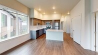 Located at 26900 SE 271st Pl in Maple Valley, WA, this one-bedroom, two-bathroom unit offers a well-designed, single-floor layout with modern finishes throughout. The open-concept kitchen serves as the centerpiece of the living area, featuring a large center island with a white quartz countertop, two-tone cabinetry combining warm wood-grain upper cabinets with gray lower cabinets, and a full suite of stainless steel appliances including a range, microwave, dishwasher, and refrigerator. A clean white backsplash and recessed lighting complete the kitchen's contemporary aesthetic, while hardwood-style flooring extends through the main living areas, enhancing the sense of openness.

The bedroom features soft carpeting, a window with outdoor views, and access to a dedicated closet. The two bathrooms are well-appointed with consistent finishes; one includes a single-sink vanity with gray cabinetry and a tub/shower combination, while the second features a dual-sink vanity with a wide mirror and a separate glass-enclosed shower. Both bathrooms include white quartz countertops and hardwood-style flooring, maintaining a cohesive modern aesthetic. Natural light flows throughout the unit via multiple windows, contributing to a bright and welcoming overall ambiance.