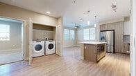 Located at 13250 Foothill Blvd in Rancho Cucamonga, CA, this well-appointed one-bedroom, one-bathroom residence offers a thoughtfully designed single-floor layout. Light-toned luxury vinyl plank flooring flows throughout the main living areas, complemented by neutral warm-beige walls that create a bright and welcoming atmosphere.

The kitchen is a standout feature, showcasing a two-tone design with crisp white upper cabinetry and natural wood-finish lower cabinets, white quartz countertops, and a classic subway tile backsplash. A central island with a built-in microwave provides additional prep space and storage. The kitchen is fully equipped with stainless steel appliances, including a gas range, dishwasher, and French door refrigerator. Pendant lighting and a ceiling fan enhance the open-concept living and dining area, which benefits from generous natural light through multiple windows with blinds.

A dedicated in-unit laundry nook with side-by-side washer and dryer adds everyday convenience. The bedroom features plush carpeting, a ceiling fan, a large window with outdoor views, and direct access to a walk-in closet. The bathroom offers a combined soaking tub and shower, finished with large-format tile surrounds and coordinating tile flooring for a clean, modern look.