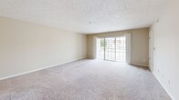 Located at 130 Eaton Ridge Dr in Northfield, OH, this two-bedroom, two-bathroom residence offers a comfortable and functional single-floor layout. The open-concept living room is generously sized, featuring plush carpeting, a textured ceiling, and a sliding glass door that floods the space with natural light and provides access to an outdoor balcony area. The kitchen is well-appointed with warm oak cabinetry, white appliances including a range, refrigerator, and dishwasher, light countertops, and easy-care hardwood-style flooring — with an adjacent dining nook complete with a ceiling fan. Both bedrooms are carpeted and feature ceiling fans with light kits, and large windows that frame green outdoor views. The spacious primary bedroom includes a walk-in closet outfitted with wire shelving for organized storage. Both bathrooms are finished with oak vanities, white countertops, tile flooring, and large mirrors. One bathroom features a full tub and shower combination. A dedicated closet provides additional storage. Neutral tones throughout create a clean, move-in-ready atmosphere, while the ample window placement ensures natural light in every room.