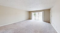 Located at 130 Eaton Ridge Dr in Northfield, OH, this two-bedroom, two-bathroom residence offers a comfortable and functional single-floor layout. The open-concept living room is generously sized, featuring plush carpeting, a textured ceiling, and a sliding glass door that floods the space with natural light and provides access to an outdoor balcony area. The kitchen is well-appointed with warm oak cabinetry, white appliances including a range, refrigerator, and dishwasher, light countertops, and easy-care hardwood-style flooring — with an adjacent dining nook complete with a ceiling fan. Both bedrooms are carpeted and feature ceiling fans with light kits, and large windows that frame green outdoor views. The spacious primary bedroom includes a walk-in closet outfitted with wire shelving for organized storage. Both bathrooms are finished with oak vanities, white countertops, tile flooring, and large mirrors. One bathroom features a full tub and shower combination. A dedicated closet provides additional storage. Neutral tones throughout create a clean, move-in-ready atmosphere, while the ample window placement ensures natural light in every room.