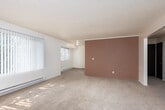 This single-floor unit is thoughtfully laid out across several well-defined spaces, as seen in the overhead floor plan. A carpeted hallway connects the main entry to the living areas and bedrooms, with a dark-toned interior door providing a visual anchor at the corridor's end.

The living area is generously sized, featuring plush carpeting, textured ceilings, and large windows that invite abundant natural light and views of surrounding greenery. A sliding glass door with vertical blinds opens to an outdoor area, offering a glimpse of what appears to be a pool or patio beyond. Baseboard heaters run along the walls, providing consistent warmth throughout.

The kitchen is galley-style, finished with warm wood cabinetry, laminate countertops, and wood-look vinyl flooring. White appliances, including a range and full-size refrigerator, are included.

The bathroom features wood-look flooring, a wood-toned vanity with granite-style countertop, a single sink, a toilet, and a soaking tub, illuminated by a small window. The bedrooms are carpeted and naturally lit, each equipped with baseboard heating. One bedroom includes a large sliding-door closet, while the other features a window with outdoor views.