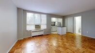 Located at 518 E Town St in Columbus, Ohio, this studio unit offers a practical and efficiently designed single-floor layout. The combined kitchen and living area serves as the heart of the space, featuring warm parquet hardwood flooring that adds classic character throughout. A window unit provides climate control, while a large window allows natural light to brighten the open living area. The kitchen is equipped with white cabinetry, a refrigerator, and an electric range, alongside a small peninsula with a dark countertop that provides a natural division between the cooking and living zones. The entrance leads seamlessly into the main living space, maintaining an open and accessible flow. Two closets offer notable storage for a unit of this size — one features built-in shelving and a hanging rod, maximizing organization potential. The bathroom is clean and functional, appointed with a full soaking tub and shower combination, white subway tile surround, a pedestal sink, and a medicine cabinet mirror. Neutral gray walls and white trim throughout the unit create a cohesive, understated aesthetic that provides a versatile backdrop for personalization. This unit is well-suited for individuals seeking a straightforward, manageable living space in a central Columbus location.