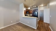 This single-floor residence is thoughtfully designed to maximize functionality and comfort. The kitchen serves as a central highlight, featuring rich dark wood cabinetry with brushed nickel hardware, granite countertops, and a full suite of black appliances including a range, built-in microwave, and refrigerator. A peninsula with a granite overhang connects the kitchen to the living area, illuminated by elegant pendant lighting and track lights overhead. The kitchen flooring is warm hardwood, providing a clean contrast to the carpeted living spaces beyond.

The living area flows naturally from the kitchen and is finished with plush carpet and a ceiling fan. A built-in shelving unit adds functional storage and visual interest, while a window dressed with blinds allows natural light to brighten the room.

The bedrooms are carpeted and generously proportioned, each equipped with ceiling fans and windows fitted with blinds. One bedroom features a tray ceiling detail, adding architectural character. A walk-in closet services one of the bedrooms, offering dual hanging rods and shelving on multiple walls, providing ample storage capacity.

Throughout the unit, neutral wall tones, textured ceilings, and consistent trim details create a cohesive and inviting atmosphere.