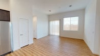 Located at 9740 E Hampton Rd. in Mesa, Arizona, this single-story home offers a clean, modern interior with a bright and open feel throughout. Light wood-look flooring runs seamlessly across the living areas, creating a warm and cohesive aesthetic that complements the crisp white walls and trim.

The open-concept living area is bathed in natural light from large windows fitted with vertical blinds and standard window coverings, providing both brightness and privacy. The space flows naturally into the kitchen, which is outfitted with rich, dark espresso-toned cabinetry in an L-shaped configuration, white countertops, a stainless steel sink, and a full suite of stainless steel appliances including a range, microwave, and dishwasher.

The bedrooms are generously proportioned, with one featuring a distinctive horizontal clerestory window that draws in additional natural light. A spacious walk-in closet with multi-level hanging rods and shelving provides ample storage.

The primary bathroom includes a large vanity with white countertop, dark cabinetry, an oversized mirror, and a glass-enclosed walk-in shower. A secondary bathroom offers similar finishes with a single-sink vanity, large mirror, and natural light from a frosted window. The home's thoughtful layout and consistent design details make it a well-organized and functional living space.