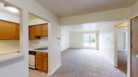 Located on Harper Ave in Clinton Township, Michigan, this 2-bedroom, 1-bathroom unit offers a practical and comfortable single-floor layout. The open-concept living and dining area is generously proportioned, featuring neutral carpet flooring, bright white walls, and a large window that invites natural light and offers pleasant outdoor greenery views. The space feels airy and versatile, well-suited for a variety of furniture arrangements. The kitchen connects directly to the living area through an open pass-through design, featuring warm-toned wood cabinetry, a built-in sink, and tile flooring — providing an efficient and accessible cooking space. The two carpeted bedrooms are quietly tucked away from the main living areas. The primary bedroom is a comfortable size, offering a closet with classic warm-toned wood bifold doors. The second bedroom also features carpet flooring and a window overlooking the tree-lined surroundings. A hallway connects the bedrooms and serves the shared full bathroom, which includes a tile-surround soaking tub and shower combination, mosaic tile flooring with a subtle blue accent pattern, a wood-trimmed vanity, and a toilet. Four closets throughout the unit provide ample storage. The consistent use of warm wood door tones and neutral finishes gives the space a cohesive, classic feel.