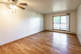 Located at 4501 Pleasant St in West Des Moines, Iowa, this single-floor unit offers a practical and functional layout with a mix of hardwood and carpeted flooring throughout. The living area features light hardwood floors, a textured ceiling, ceiling fan, and a sliding glass door that opens onto a private balcony, providing views of the surrounding greenery and neighborhood. Baseboard heating units are present throughout the space, ensuring consistent warmth.

The kitchen is equipped with wood-trimmed cabinetry featuring white panel fronts, offering ample storage. Appliances include a white electric range, dishwasher, refrigerator, built-in microwave, and a double-basin stainless steel sink set into a light countertop. The kitchen connects seamlessly to the main living area via an open archway.

Bedrooms are carpeted and well-lit by windows with vertical blinds, each accompanied by baseboard heating. The bathroom includes a full-size soaking tub and shower combination with a curtain rod, a toilet, and wood-tone flooring, maintaining a clean and neutral aesthetic.

Overall, the space presents a straightforward, functional design with neutral tones, natural light, and practical amenities throughout.