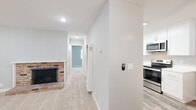 Located at 930 Rockefeller Dr in Sunnyvale, CA, this single-floor residence offers a well-organized layout comprising a living room, kitchen, and one bedroom. The living room is a comfortable, carpeted space anchored by a classic brick fireplace with a raised hearth, recessed lighting overhead, and soft neutral-toned walls that create a clean, welcoming atmosphere. A window near the entry allows natural light to filter in through blinds, brightening the space.

The kitchen is a standout feature, outfitted with crisp white shaker cabinetry, white quartz countertops, and light wood-tone flooring. A full suite of stainless steel appliances — including a refrigerator, electric range, microwave, and dishwasher — provides modern functionality, while a skylight adds an extra source of natural light above.

The bedroom is generously proportioned, finished with soft carpeting and cool gray walls. It includes a mirrored sliding-door closet offering ample storage, and a window with blinds that brings in natural light. Notably, an in-unit laundry area is accessible directly from the bedroom, adding significant convenience.

A central hallway connects all areas of the home, maintaining a logical and efficient flow. Throughout the unit, fresh white trim, consistent neutral tones, and updated finishes contribute to a clean, move-in-ready presentation.