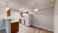 Located at 3105 East Assembly Road in Spokane, Washington, Unit A111 is a thoughtfully designed single-floor residence that combines functionality with comfortable living. The open-concept living area features warm wood-look vinyl flooring, neutral-toned walls, and a sliding glass door that fills the space with natural light while providing direct access to the outdoors. A convenient entry closet greets residents at the front door, offering immediate storage upon arrival.

The kitchen is well-equipped with warm wood cabinetry, a peninsula countertop with a double sink, white appliances including a refrigerator, electric range with overhead microwave, and a dishwasher. Pendant lighting above the peninsula adds a welcoming ambiance to the cooking and dining area.

The bathroom is appointed with wood-toned cabinetry, a wide vanity mirror with overhead lighting, and wood-look flooring that carries throughout. A dedicated linen closet with built-in wire shelving provides ample storage. The unit also features a dedicated laundry room complete with a full-size washer and dryer, adding a high level of convenience to daily living. Additional shelving in the laundry area offers extra organizational space. Throughout, baseboard heating ensures year-round comfort in this clean, move-in-ready Spokane residence.