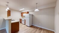 Located at 3105 East Assembly Road in Spokane, Washington, Unit A111 is a thoughtfully designed single-floor residence that combines functionality with comfortable living. The open-concept living area features warm wood-look vinyl flooring, neutral-toned walls, and a sliding glass door that fills the space with natural light while providing direct access to the outdoors. A convenient entry closet greets residents at the front door, offering immediate storage upon arrival.

The kitchen is well-equipped with warm wood cabinetry, a peninsula countertop with a double sink, white appliances including a refrigerator, electric range with overhead microwave, and a dishwasher. Pendant lighting above the peninsula adds a welcoming ambiance to the cooking and dining area.

The bathroom is appointed with wood-toned cabinetry, a wide vanity mirror with overhead lighting, and wood-look flooring that carries throughout. A dedicated linen closet with built-in wire shelving provides ample storage. The unit also features a dedicated laundry room complete with a full-size washer and dryer, adding a high level of convenience to daily living. Additional shelving in the laundry area offers extra organizational space. Throughout, baseboard heating ensures year-round comfort in this clean, move-in-ready Spokane residence.