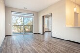 Located at 142 Paoli St in Verona, Wisconsin, this thoughtfully designed 2-bedroom, 1-bathroom residence offers a contemporary living experience across a single, efficiently laid-out floor. The open-concept great room seamlessly combines the living, dining, and kitchen areas, creating an inviting and versatile space filled with natural light. The kitchen is a standout feature, boasting a generous white quartz island with an undermount sink, rich dark-toned cabinetry, subway tile backsplash, stainless steel appliances, and stylish pendant lighting. A distinctive sliding barn door adds a modern industrial touch to the kitchen entry. The living area extends to a private balcony enclosed with sleek cable railings, offering pleasant views of the surrounding wooded landscape. Wood-style plank flooring runs throughout the main living areas, while the bedrooms are finished with soft carpeting and feature windows that frame natural outdoor scenery. The spacious primary bedroom provides a comfortable retreat with ample closet space. Three closets total are distributed throughout the unit. The bathroom is conveniently situated alongside a dedicated laundry area with a stacked washer and dryer. Clean neutral walls and modern finishes throughout contribute to the home's bright, contemporary ambiance.