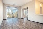Located at 142 Paoli St in Verona, Wisconsin, this thoughtfully designed 2-bedroom, 1-bathroom residence offers a contemporary living experience across a single, efficiently laid-out floor. The open-concept great room seamlessly combines the living, dining, and kitchen areas, creating an inviting and versatile space filled with natural light. The kitchen is a standout feature, boasting a generous white quartz island with an undermount sink, rich dark-toned cabinetry, subway tile backsplash, stainless steel appliances, and stylish pendant lighting. A distinctive sliding barn door adds a modern industrial touch to the kitchen entry. The living area extends to a private balcony enclosed with sleek cable railings, offering pleasant views of the surrounding wooded landscape. Wood-style plank flooring runs throughout the main living areas, while the bedrooms are finished with soft carpeting and feature windows that frame natural outdoor scenery. The spacious primary bedroom provides a comfortable retreat with ample closet space. Three closets total are distributed throughout the unit. The bathroom is conveniently situated alongside a dedicated laundry area with a stacked washer and dryer. Clean neutral walls and modern finishes throughout contribute to the home's bright, contemporary ambiance.