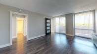 This thoughtfully renovated single-floor residence at 2000 Riverside Dr in Richmond, Virginia offers a clean, modern aesthetic throughout. The open layout is anchored by dark hardwood-style flooring in the main living area, which is bathed in natural light from large sliding glass doors that lead to an outdoor space. A striking black barn door with frosted glass panels serves as a stylish architectural focal point, adding a contemporary industrial touch to the living space.

The kitchen has been updated with white shaker-style cabinetry, speckled granite countertops, a stainless steel undermount sink with a brushed nickel pull-down faucet, and a glossy gray subway tile backsplash. A built-in dishwasher completes the functional layout.

The bedroom features lighter hardwood-style flooring, neutral gray walls, and a large window with blinds that bring in abundant natural light and outdoor views. A wall-mounted heating unit provides climate control.

The bathroom is finished in a clean, minimalist style with white cabinetry, brushed nickel hardware, a white vanity countertop, wood-look flooring, and a full tub-shower combination. Recessed lighting adds a polished touch. Overall, the space presents a cohesive, updated interior well-suited for comfortable everyday living.