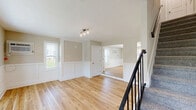 Located at 644 Kline Ave in Pottstown, PA, this two-story home offers a thoughtfully updated interior across two well-proportioned floors. The main level features a bright living room with light hardwood flooring, classic white wainscoting panels, large windows that invite natural light, and a track lighting fixture overhead. A staircase with sleek metal railing connects the floors seamlessly. The kitchen is a standout, outfitted with white shaker cabinets, quartz countertops, a decorative geometric tile backsplash, stainless steel appliances, and pendant lighting above the breakfast bar peninsula. Upstairs, the spacious primary bedroom features plush carpet, multiple windows with outdoor views, and a wall-mounted AC unit. It also boasts generous closet space, highlighted by three paneled doors. The second bedroom mirrors the warm, neutral tones found throughout the home and includes wainscoting detailing. The full bathroom is elegantly finished with marble-style wall tiles, a contrasting black subway tile accent border, and a full tub-shower combination. Consistent neutral paint tones, hardwood flooring on the main level, and carpet upstairs create a cohesive and inviting atmosphere throughout this well-appointed home.