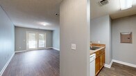 Located at 391 Old Griffin Rd in McDonough, GA, this one-bedroom, one-bathroom unit is thoughtfully laid out across a single floor. Wood-style flooring flows continuously throughout the space, complemented by soft gray walls and textured ceilings that lend a clean, cohesive aesthetic.

The combined living and dining area forms the heart of the unit, offering a generous, open feel with abundant natural light streaming through a set of double glass doors that lead directly to a private balcony — ideal for enjoying outdoor views.

The kitchen is positioned adjacent to the living area, separated by a structural column that provides a semi-open feel. It features warm wood-toned cabinetry, laminate countertops, a built-in sink, a dishwasher, and white appliances including a range and refrigerator.

The bedroom is a comfortable, well-proportioned room with a window that brings in natural light. It connects to a hallway that provides access to two closets, offering ample storage. A dedicated laundry area and utility room add practical convenience to the layout.

A full bathroom and a hallway complete the floorplan, making this a fully functional and efficiently designed single-level residence.