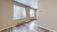 This efficiently designed studio unit at 334 Wells Ave S in Renton, Washington offers a well-organized single-floor layout comprising a living area, kitchenette, and a full bathroom. The living space is finished with light gray wood-look vinyl plank flooring that flows seamlessly throughout, lending a clean and cohesive aesthetic. Neutral warm-beige walls keep the interior bright and versatile. Two windows along the living area's exterior wall allow natural light to fill the space, complemented by baseboard heating beneath each window for year-round comfort. A built-in wall shelf provides convenient storage or display space, while a large wall-spanning sliding closet with warm oak-toned wood panel doors offers generous storage capacity. The kitchenette, visible in the floorplan view, includes white cabinetry and essential appliances. The bathroom features a streamlined vanity with light wood cabinetry, a white countertop with integrated sink, and consistent vinyl plank flooring that matches the rest of the unit. Grab bars and a towel bar are installed, adding practical accessibility. The overall design is clean, functional, and move-in ready, making this a practical unit in a convenient Renton location.
