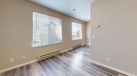 This efficiently designed studio unit at 334 Wells Ave S in Renton, Washington offers a well-organized single-floor layout comprising a living area, kitchenette, and a full bathroom. The living space is finished with light gray wood-look vinyl plank flooring that flows seamlessly throughout, lending a clean and cohesive aesthetic. Neutral warm-beige walls keep the interior bright and versatile. Two windows along the living area's exterior wall allow natural light to fill the space, complemented by baseboard heating beneath each window for year-round comfort. A built-in wall shelf provides convenient storage or display space, while a large wall-spanning sliding closet with warm oak-toned wood panel doors offers generous storage capacity. The kitchenette, visible in the floorplan view, includes white cabinetry and essential appliances. The bathroom features a streamlined vanity with light wood cabinetry, a white countertop with integrated sink, and consistent vinyl plank flooring that matches the rest of the unit. Grab bars and a towel bar are installed, adding practical accessibility. The overall design is clean, functional, and move-in ready, making this a practical unit in a convenient Renton location.