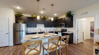 This single-story residence showcases a thoughtfully designed open layout with consistent, high-quality finishes throughout. The kitchen serves as a central highlight, featuring dark espresso-toned shaker-style cabinetry extending to the ceiling and accented with greenery atop. Light granite countertops provide a striking contrast, complemented by a full suite of stainless steel appliances including a refrigerator, range, and microwave. A spacious island with pendant lighting above offers casual bar seating for multiple guests, making it an ideal space for both meal preparation and entertaining.

The living room is bright and welcoming, with a bank of windows allowing natural light to filter in and offering exterior views. Wood-look plank flooring runs throughout the main living areas, lending warmth and visual continuity to the open-concept space.

The bedrooms are carpeted for comfort, each featuring neutral wall tones and windows that allow natural light. The primary bedroom includes direct access to an en-suite bathroom. Bathrooms throughout maintain the design consistency of the home, featuring dark vanity cabinetry with granite countertops, wood-look flooring, and clean white fixtures. One bathroom includes a tub-shower combination, while another presents a streamlined vanity layout ideal for a secondary bath.