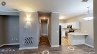 Located at 5544 Sunlight Dr in Durham, NC, this one-bedroom, two-bathroom residence offers a thoughtfully arranged single-floor layout with modern finishes throughout. Rich wood-look flooring flows seamlessly across the main living areas and hallways, creating a warm, cohesive aesthetic complemented by neutral gray walls and crisp white trim.

The kitchen is a standout feature, outfitted with white shaker-style cabinetry, light quartz countertops, a classic subway tile backsplash, and a full suite of stainless steel appliances including a refrigerator, electric range, over-the-range microwave, and dishwasher. A peninsula provides additional counter space and a natural transition point between the kitchen and living areas.

The generously sized primary bedroom accommodates a variety of furniture arrangements and is brightened by two windows offering views of surrounding greenery. A ceiling fan with integrated lighting adds comfort and function. The bedroom connects to a well-appointed en-suite bathroom featuring a single vanity with white countertop, a large mirror, and access to a dedicated walk-in closet with wire shelving. A second bathroom serves the rest of the unit. Two hallways connect the spaces efficiently, and wall-mounted sconces provide warm accent lighting throughout.