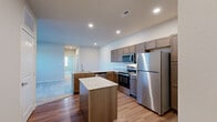 Located at Hawk Ridge Trail in Lake Saint Louis, Missouri, this single-floor, 3-bedroom, 2-bathroom apartment offers a well-designed layout with a clean, contemporary aesthetic. The kitchen is a standout feature, equipped with stainless steel appliances including a refrigerator, range, and over-the-range microwave, complemented by rich medium-toned cabinetry, light granite countertops, and a central island that provides additional prep space and storage. Recessed lighting illuminates the kitchen and adjacent areas, enhancing the bright, open feel. The kitchen flows into a connected living area, and a door leads out to a private outdoor space with views of the surrounding landscape, bringing in natural light. The bedrooms are carpeted in a neutral tone, offering a comfortable and quiet retreat, with windows that allow for natural light. Arched interior doors add a subtle architectural detail throughout the unit. The bathrooms feature wood-style flooring, a vanity with warm-toned cabinetry, and a glass-enclosed shower stall. The overall color palette is neutral and light, creating a cohesive and inviting atmosphere throughout the home.