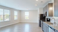 Located at 800 E Long Street in Columbus, Ohio, this single-floor, 2-bedroom, 2-bathroom residence offers a thoughtfully designed layout with contemporary finishes throughout. The open-concept kitchen and living area serves as the heart of the unit, featuring light wood-style luxury vinyl plank flooring that flows seamlessly through the main living spaces. The kitchen is outfitted with gray shaker-style cabinetry, granite countertops, a subway tile backsplash, stainless steel appliances including a refrigerator, range, microwave, and dishwasher, and a pendant light accent. Multiple windows in the living area admit generous natural light and offer views of the surrounding Columbus streetscape.

The hallway connects the living spaces to both bedrooms and bathrooms via modern dark-paneled interior doors. The primary bedroom is a well-proportioned retreat with plush carpet, multiple windows, and direct access to a private bathroom and a walk-in closet with wire shelving. The primary bathroom features a walk-in shower with sliding glass doors and brushed nickel fixtures. The second bedroom is also carpeted with a bright window. Two full bathrooms and a dedicated closet round out this well-appointed residence.