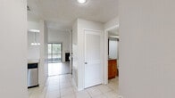 Located in Sun Valley Village in Altamonte Springs, Florida, this two-bedroom, two-bathroom two-story home offers a well-designed layout across two floors. The main level provides generous living space, highlighted by soaring vaulted ceilings and light wood-style flooring. The living room is a standout, featuring a fireplace, a ceiling fan, an elegant chandelier, and sliding glass doors that invite abundant natural light and outdoor views. A built-in shelving nook adds a functional accent. The kitchen is equipped with stainless steel appliances, granite countertops, and crisp white cabinetry, with tile flooring extending through the main-level common areas. A hallway connects to a full bathroom featuring a wood-toned vanity with granite countertop and a tiled tub-shower combination. Upstairs, the primary bedroom offers a spacious, carpeted retreat with a ceiling fan, while the second bedroom is similarly carpeted and naturally lit through slatted blinds with neighborhood views. A second full bathroom on this level includes a granite-top vanity, tile flooring, and a walk-in shower area. Both floors include closet storage. The textured ceilings and clean white walls throughout provide a bright, neutral backdrop suited to a variety of interior styles.