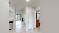 Located in Sun Valley Village in Altamonte Springs, Florida, this two-bedroom, two-bathroom two-story home offers a well-designed layout across two floors. The main level provides generous living space, highlighted by soaring vaulted ceilings and light wood-style flooring. The living room is a standout, featuring a fireplace, a ceiling fan, an elegant chandelier, and sliding glass doors that invite abundant natural light and outdoor views. A built-in shelving nook adds a functional accent. The kitchen is equipped with stainless steel appliances, granite countertops, and crisp white cabinetry, with tile flooring extending through the main-level common areas. A hallway connects to a full bathroom featuring a wood-toned vanity with granite countertop and a tiled tub-shower combination. Upstairs, the primary bedroom offers a spacious, carpeted retreat with a ceiling fan, while the second bedroom is similarly carpeted and naturally lit through slatted blinds with neighborhood views. A second full bathroom on this level includes a granite-top vanity, tile flooring, and a walk-in shower area. Both floors include closet storage. The textured ceilings and clean white walls throughout provide a bright, neutral backdrop suited to a variety of interior styles.