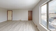 Located at 4979 S Washington Rd in Saginaw, Michigan, this two-bedroom, one-bathroom unit offers a practical and comfortable single-floor layout. The open living and dining area is finished with light hardwood-style flooring and neutral gray walls, creating a bright and airy atmosphere. Large windows allow natural light to flow throughout, enhancing the clean, understated aesthetic. The living space connects seamlessly to the combined dining and kitchen area, which features warm wood cabinetry, a marble-style countertop, a double sink, and white appliances including a range and refrigerator. A hallway leads to the two carpeted bedrooms, each finished with neutral tones and ceiling light fixtures. The primary bedroom is a comfortable size and includes direct access to a private balcony through a sliding glass door, offering views of the open surrounding landscape. The second bedroom features a built-in closet with louvered bifold doors. Both bedrooms benefit from natural light through windows. The full bathroom includes a vanity with white cabinetry, a tub/shower combination, and light hardwood-style flooring. Additional storage is provided by two closets accessible from the hallway. The balcony extends the living space outdoors, overlooking an expansive open field.