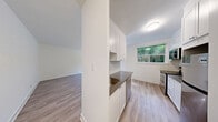 Located at 611 Woodbine Ave in Toronto's desirable East End neighbourhood, this thoughtfully renovated one-bedroom, one-bathroom unit offers a clean, modern aesthetic throughout its single floor. Light-toned hardwood-style flooring runs continuously through the space, creating a cohesive and airy feel.

The kitchen is a standout feature, showcasing white shaker-style cabinetry, dark countertops, and a classic subway tile backsplash. Stainless steel appliances — including a range, over-the-range microwave, and refrigerator — complete the well-appointed cooking space. A window above the kitchen area frames a lush, green outdoor view, filling the room with natural light.

The living area is open and versatile, offering a blank canvas for various furniture arrangements. The bedroom is a comfortable size, featuring soft neutral walls, light flooring, a classic cast iron radiator, and a window with a serene view of surrounding greenery — providing both natural light and a peaceful ambiance. Clean white panel doors connect the rooms with a tidy, consistent design.

The bathroom features a full soaking tub enclosed by crisp white subway tiles and chrome fixtures, lending a timeless, polished look. Throughout the unit, the bright white walls and natural light create a welcoming, move-in ready environment well-suited to those seeking a stylish home in Toronto's vibrant East End.